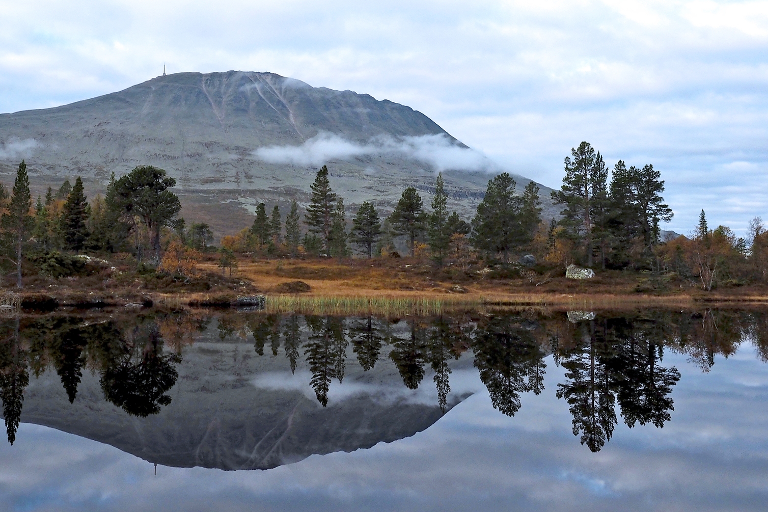 Gaustatoppen speglar sig i en stilla fj&auml;llsj&ouml;. Foto: Thomas Reinhardt.
