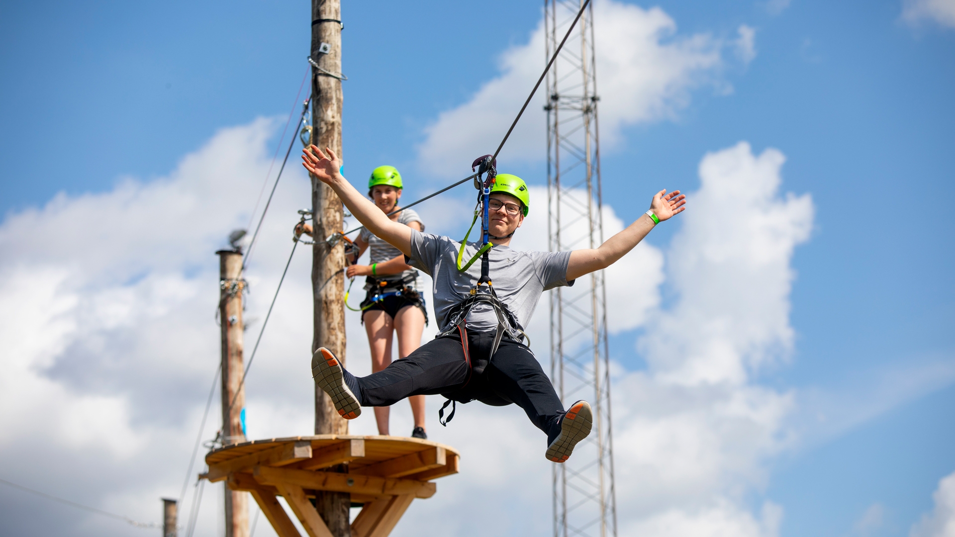 Personer som &aring;ker zipline i en h&ouml;gh&ouml;jdsbana p&aring; en solig dag.